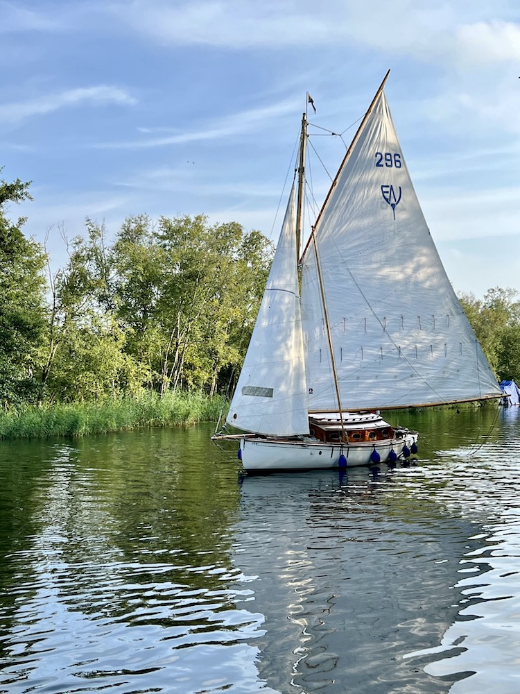 A yacht sailing along the water in the Norfolk Broads