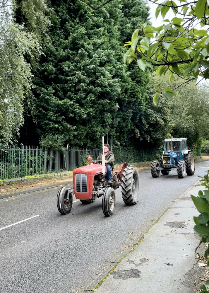 vintage tractors driving through the village