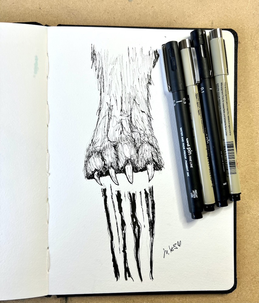 sketchbook and drawing of a wolf paw with scratches and finaliser pens